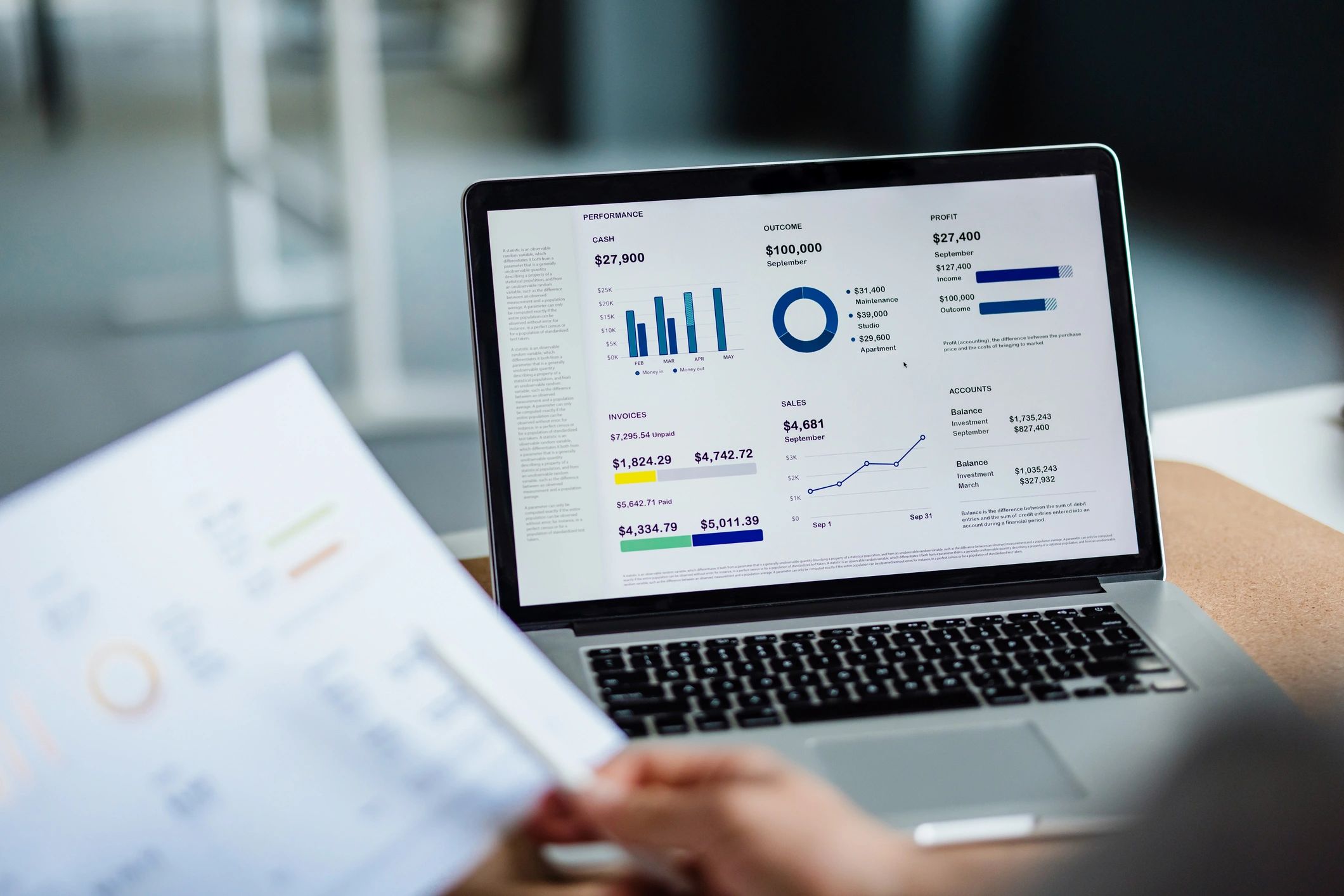 Hands reviewing a business report next to a laptop